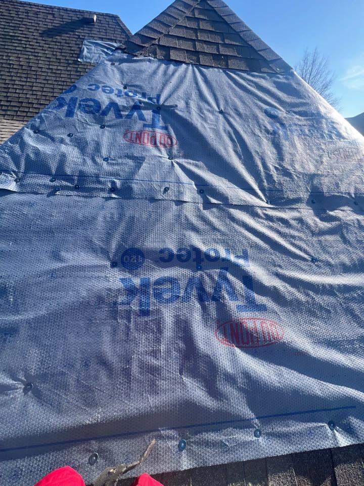 Blue tarp-covered tent-like structure under a clear sky, with printed logos visible.