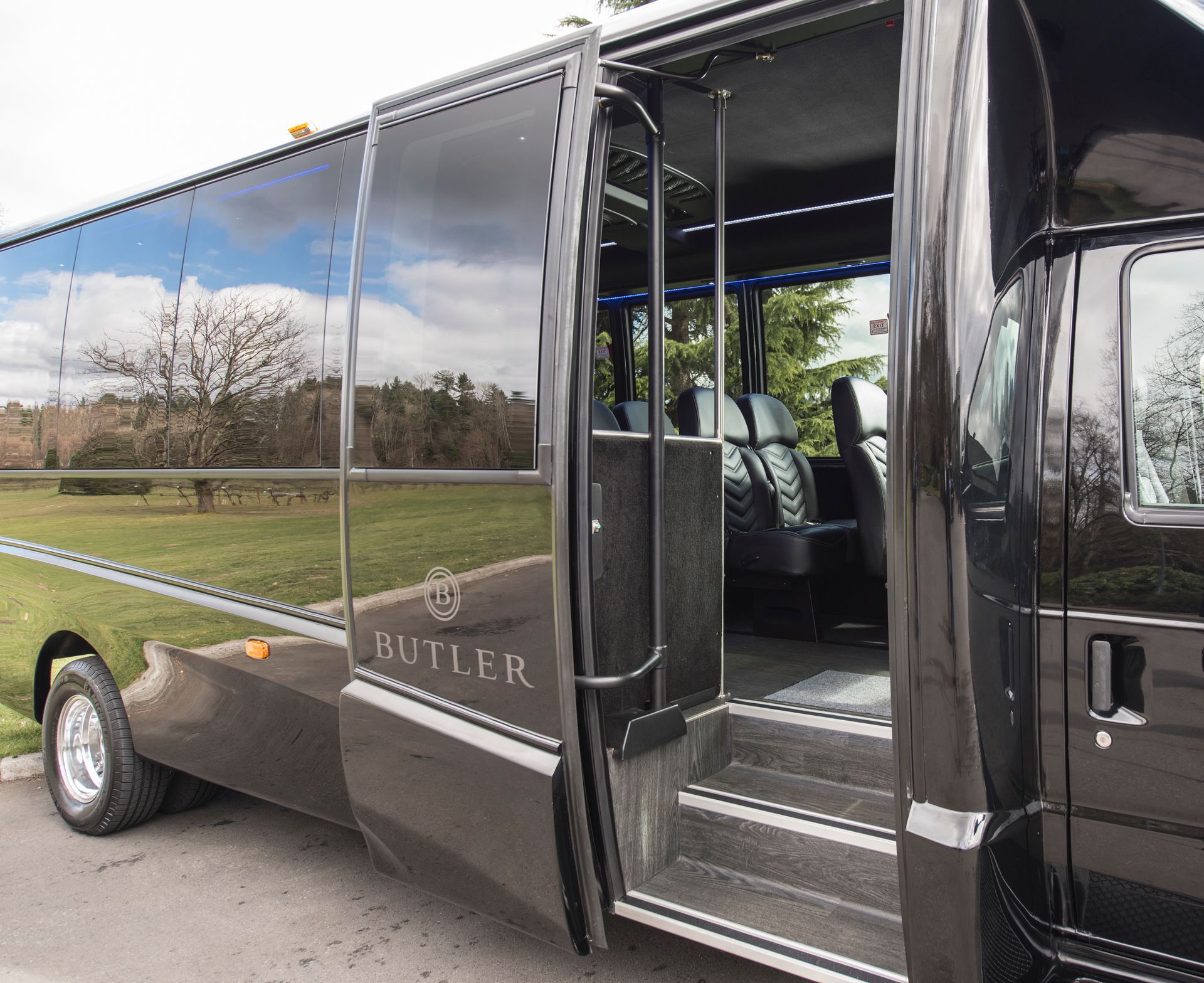 Black shuttle bus with open side door and tinted windows parked roadside