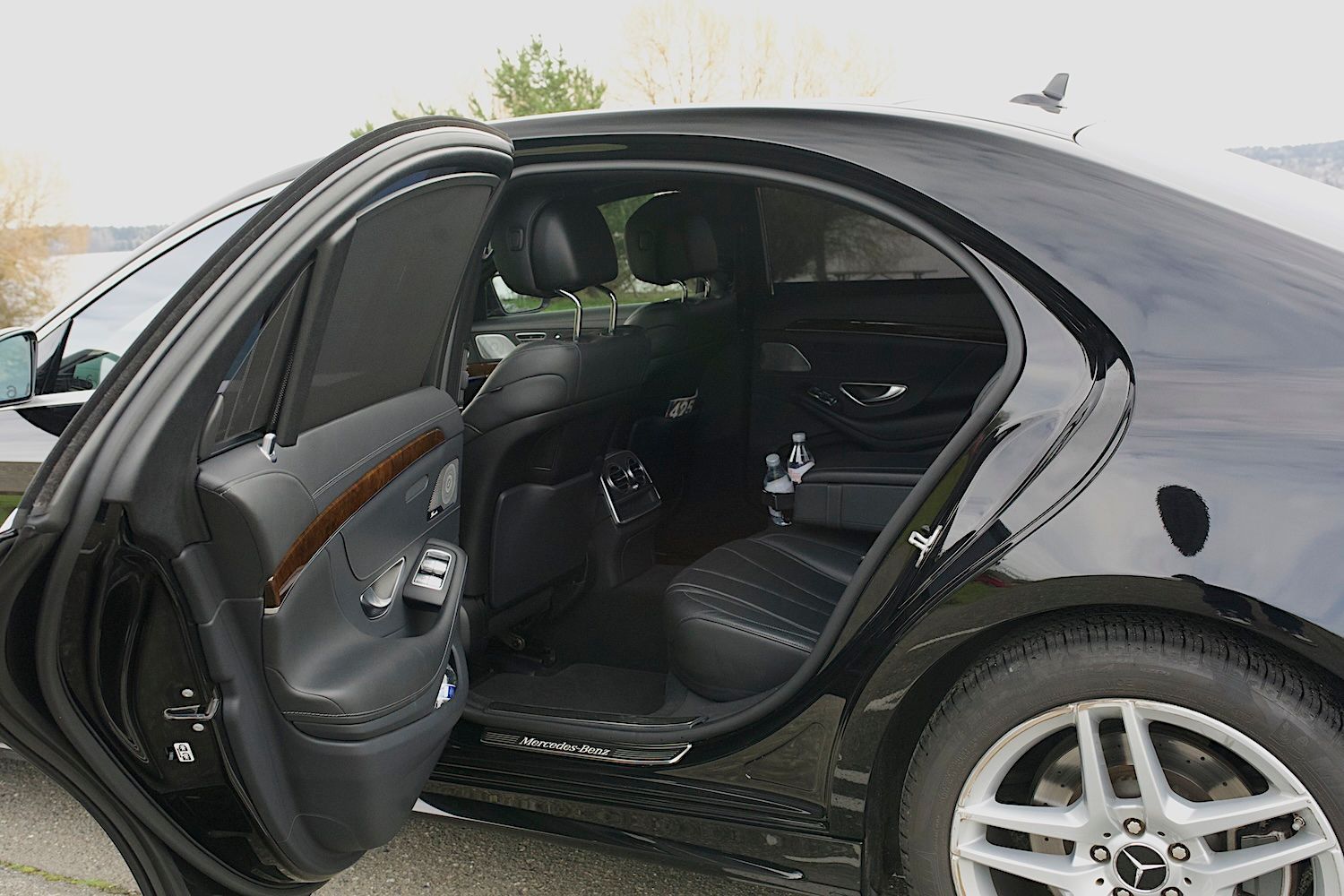 Open rear door of a black sedan, showing the dark interior and rear seats.