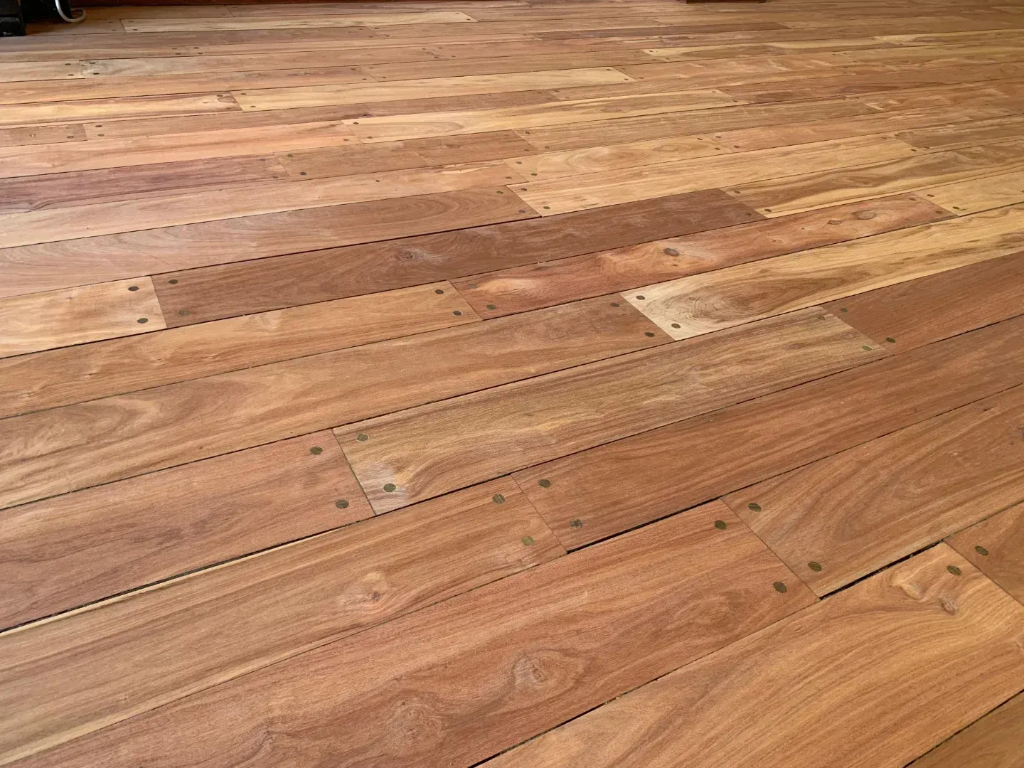 Primer plano de un suelo de madera con tablones de diferentes tonos de marrón y vetas visibles.