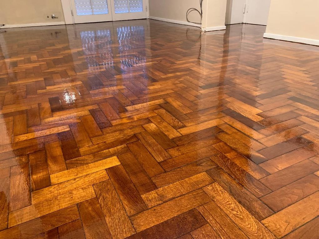 Suelo de madera brillante en espiga en una habitación vacía con reflejos de las ventanas.