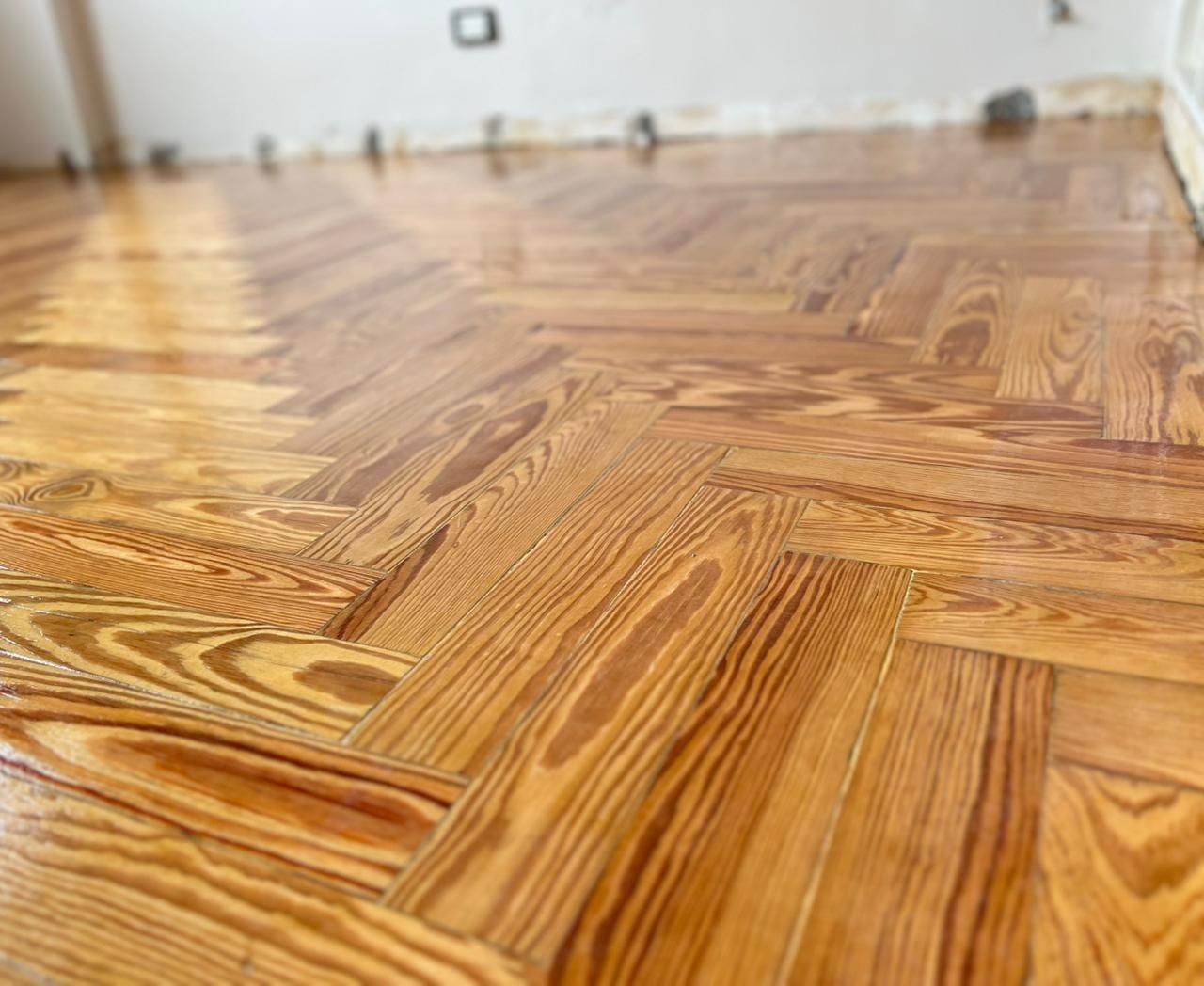 Suelo de parqué de madera brillante con estampado en una habitación luminosa y vacía.