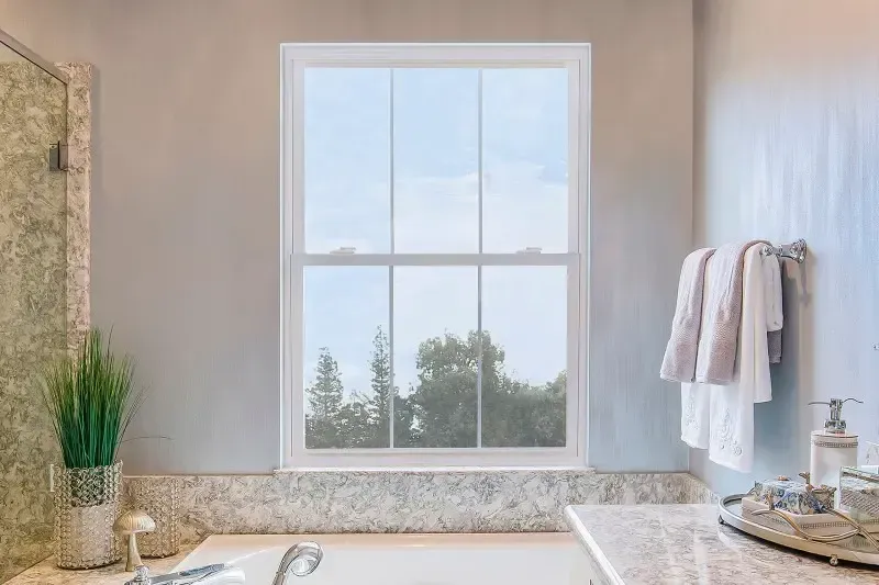 An Anlin Window over a tub in a bathroom looks out to trees