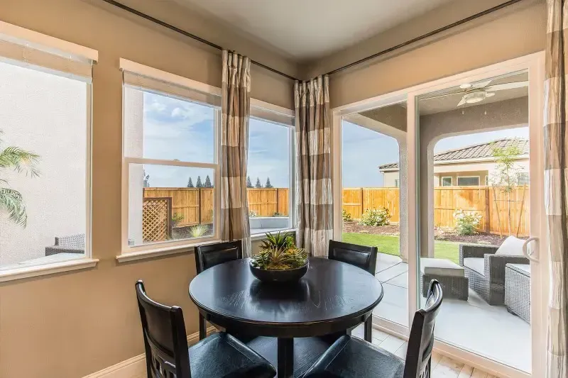 A dining room with a round table and chairs and sliding glass doors leading to a patio.