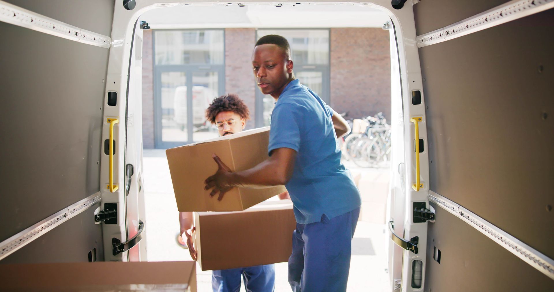 two men are loading boxes into a van