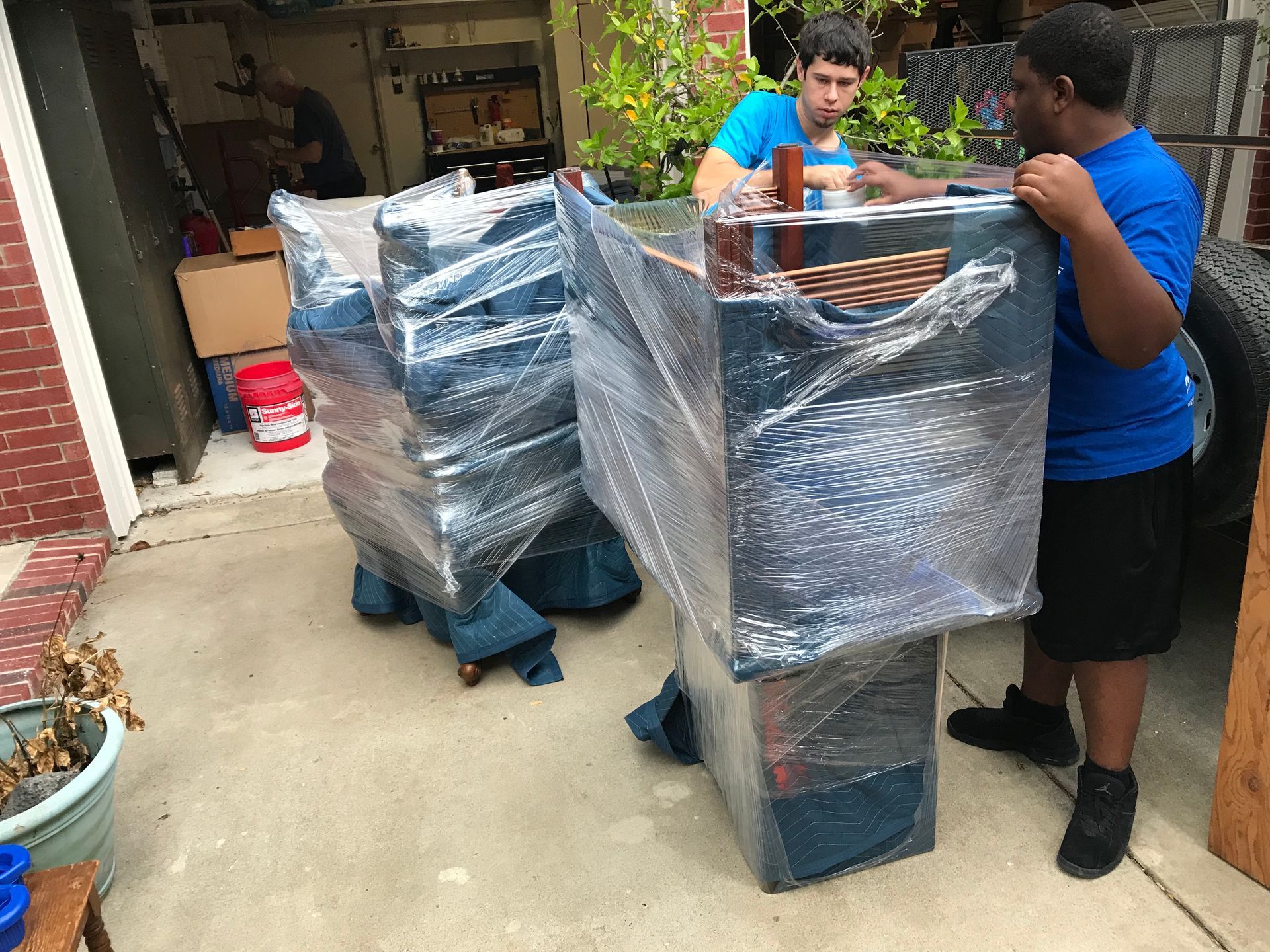 two movers are holding a chair and a rug in front of a van