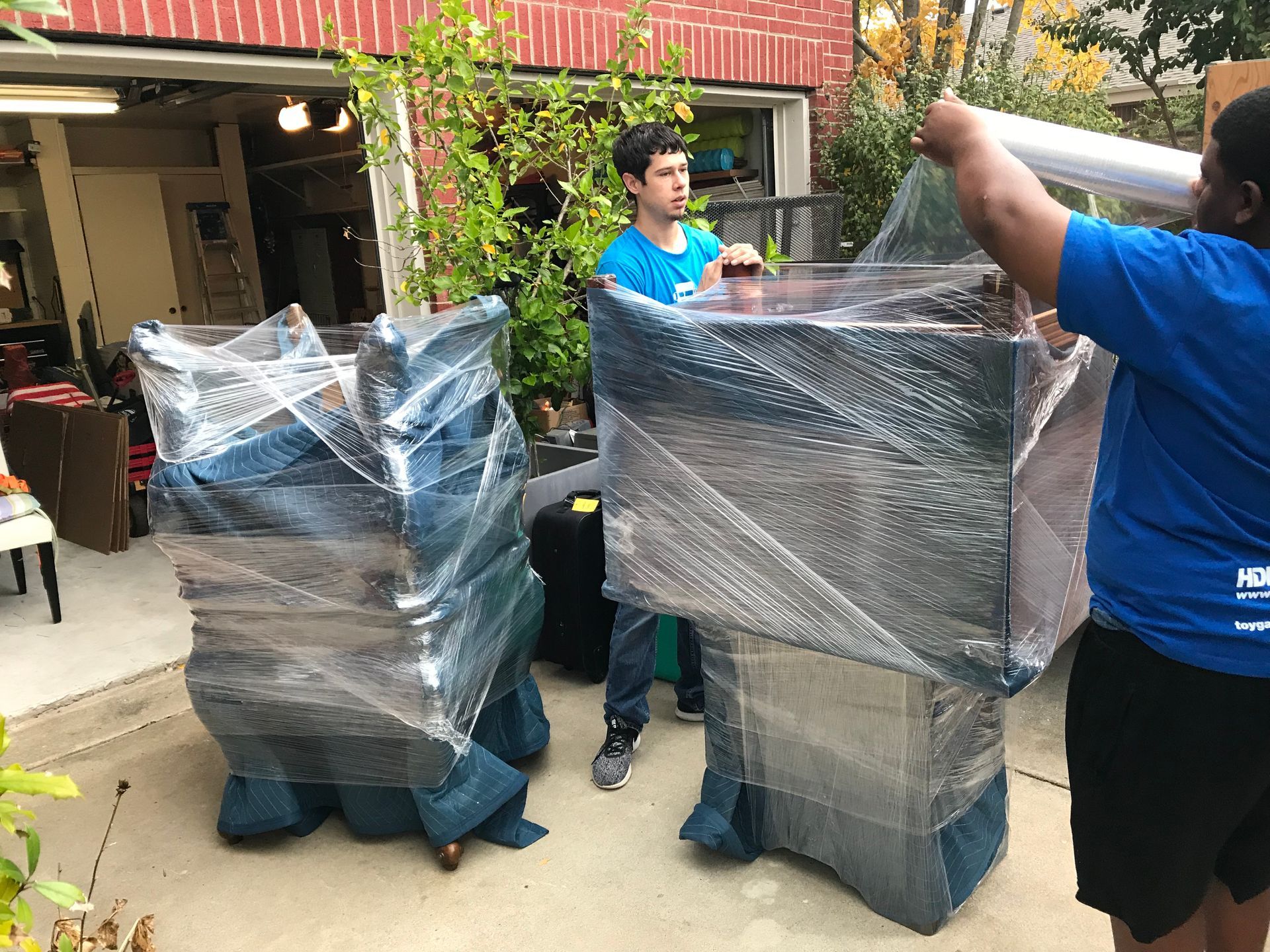 a man in a blue shirt is wrapping a piece of furniture in plastic wrap