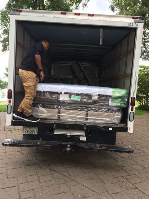 a man is loading a mattress into the back of a truck