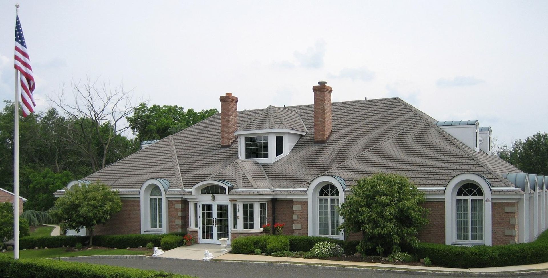 Single-story suburban house with a gray roof, white trim, and an American flag in front