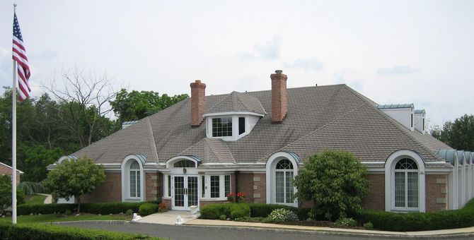 Single-story suburban house with a gray roof, white trim, and an American flag in front