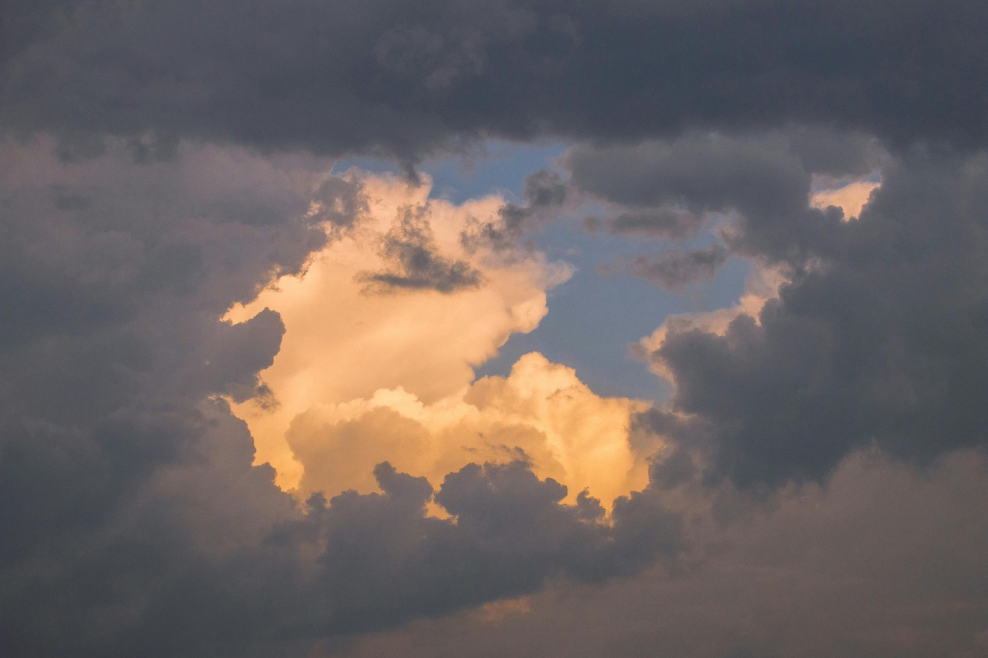 Orange sunlit clouds against a dark cloudy sky
