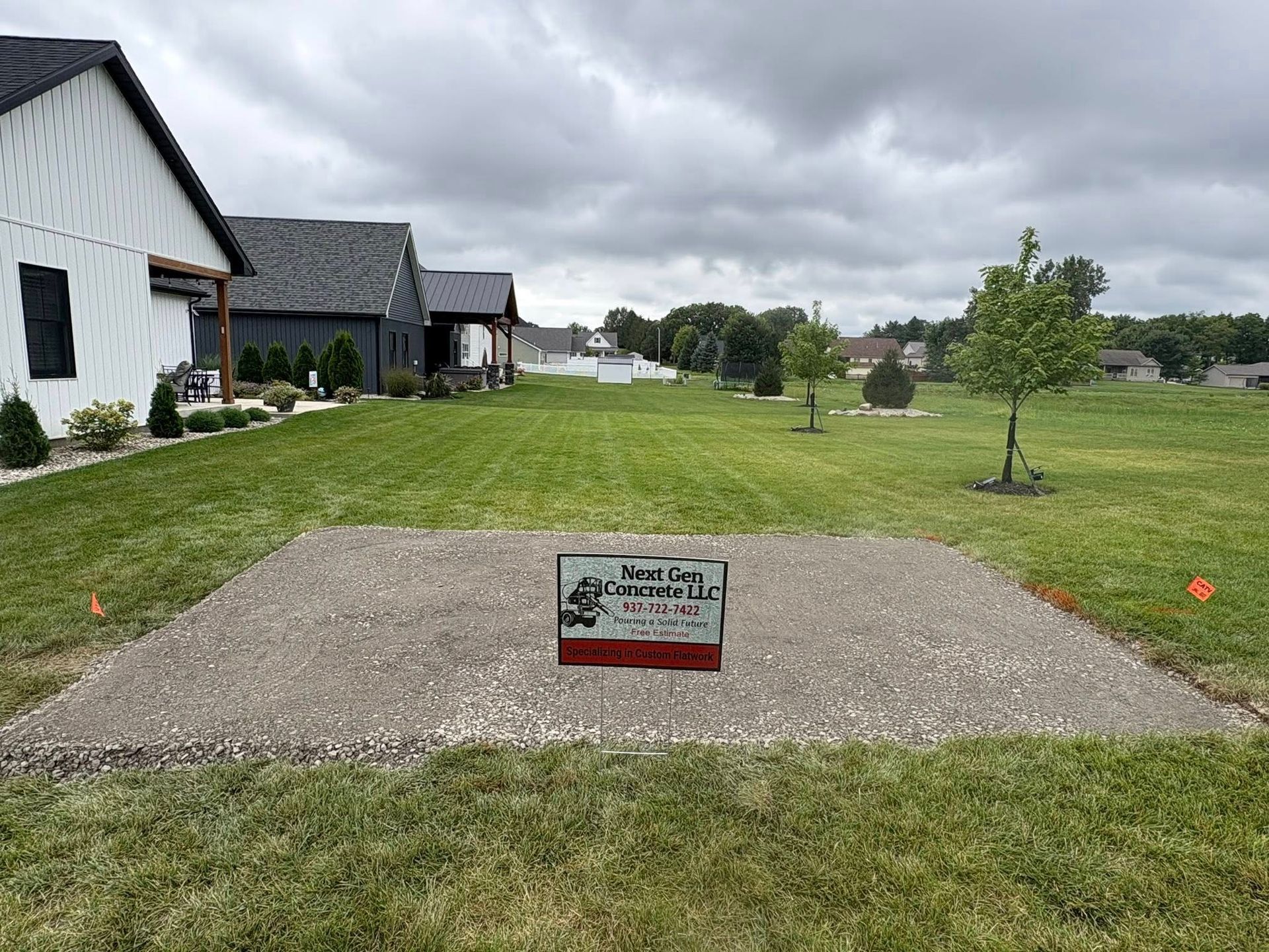 A concrete pad sits in a grassy residential lot with a small 