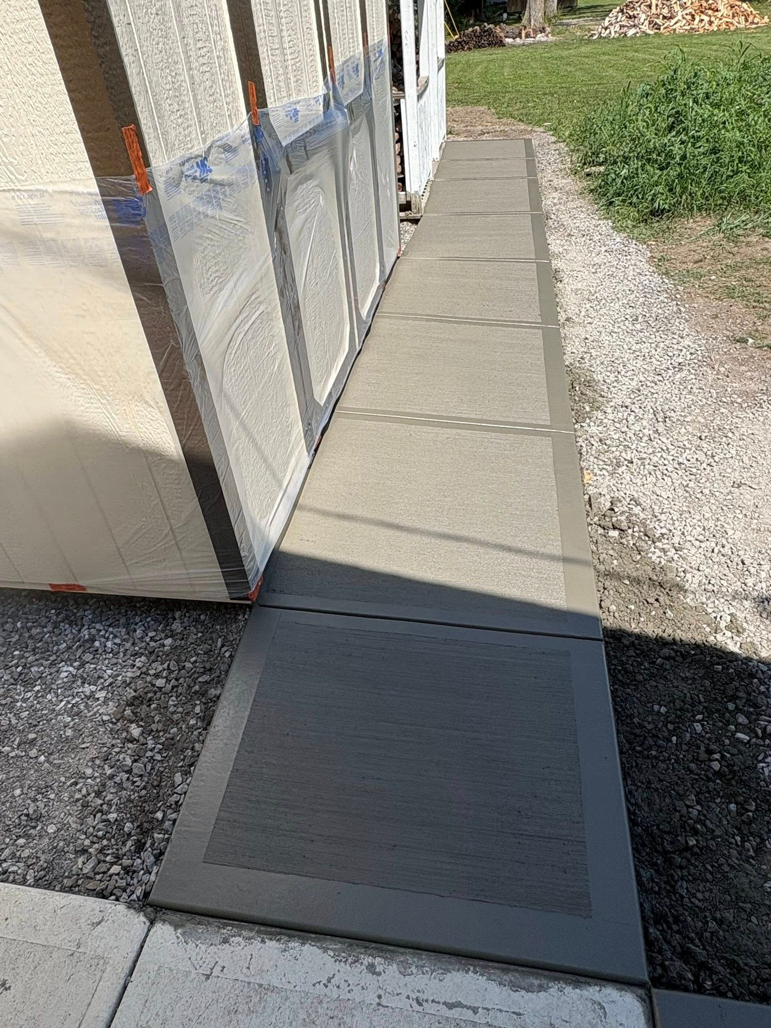 A narrow, textured rubber pathway runs along the side of a building, transitioning from dark square mats to lighter tiles.
