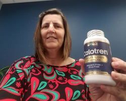 Woman holding a bottle of Calotren weight loss formula, smiling in front of a blue background.