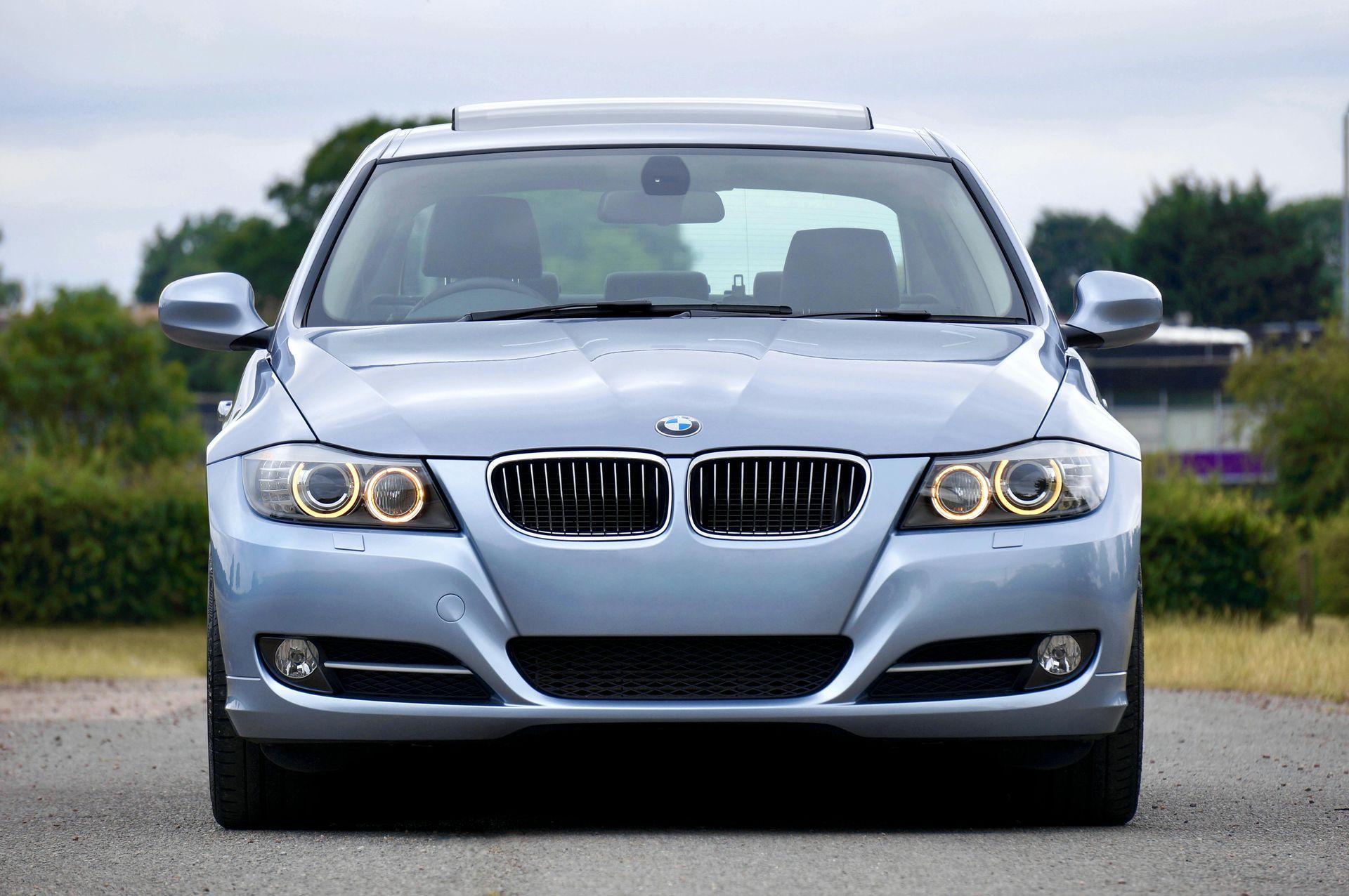 A silver bmw is parked on the side of the road.