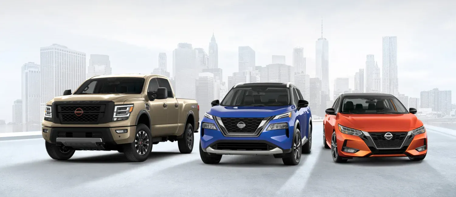 Three nissan cars are parked next to each other on a city street.