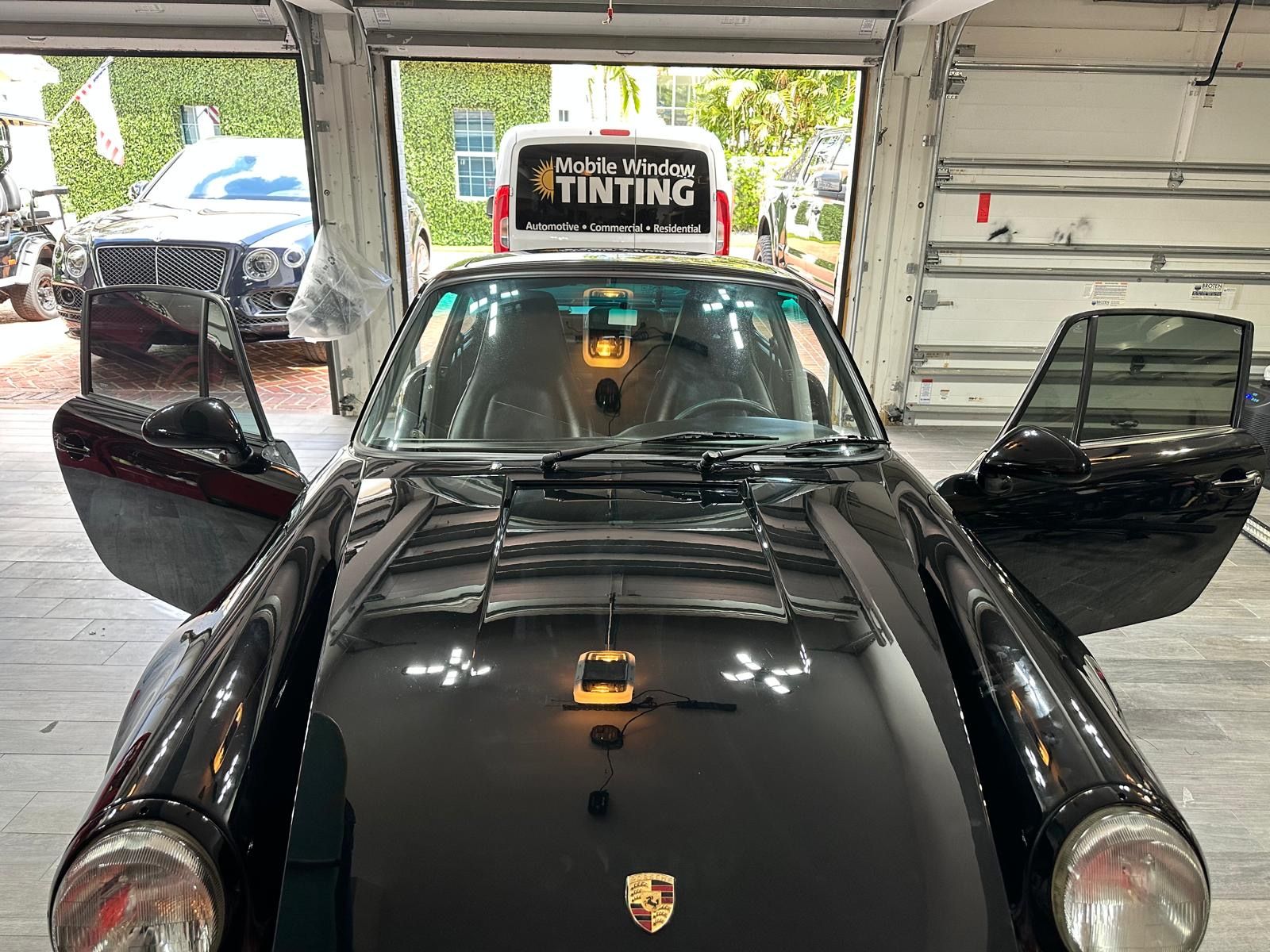 A black car is parked in a garage with its doors open.