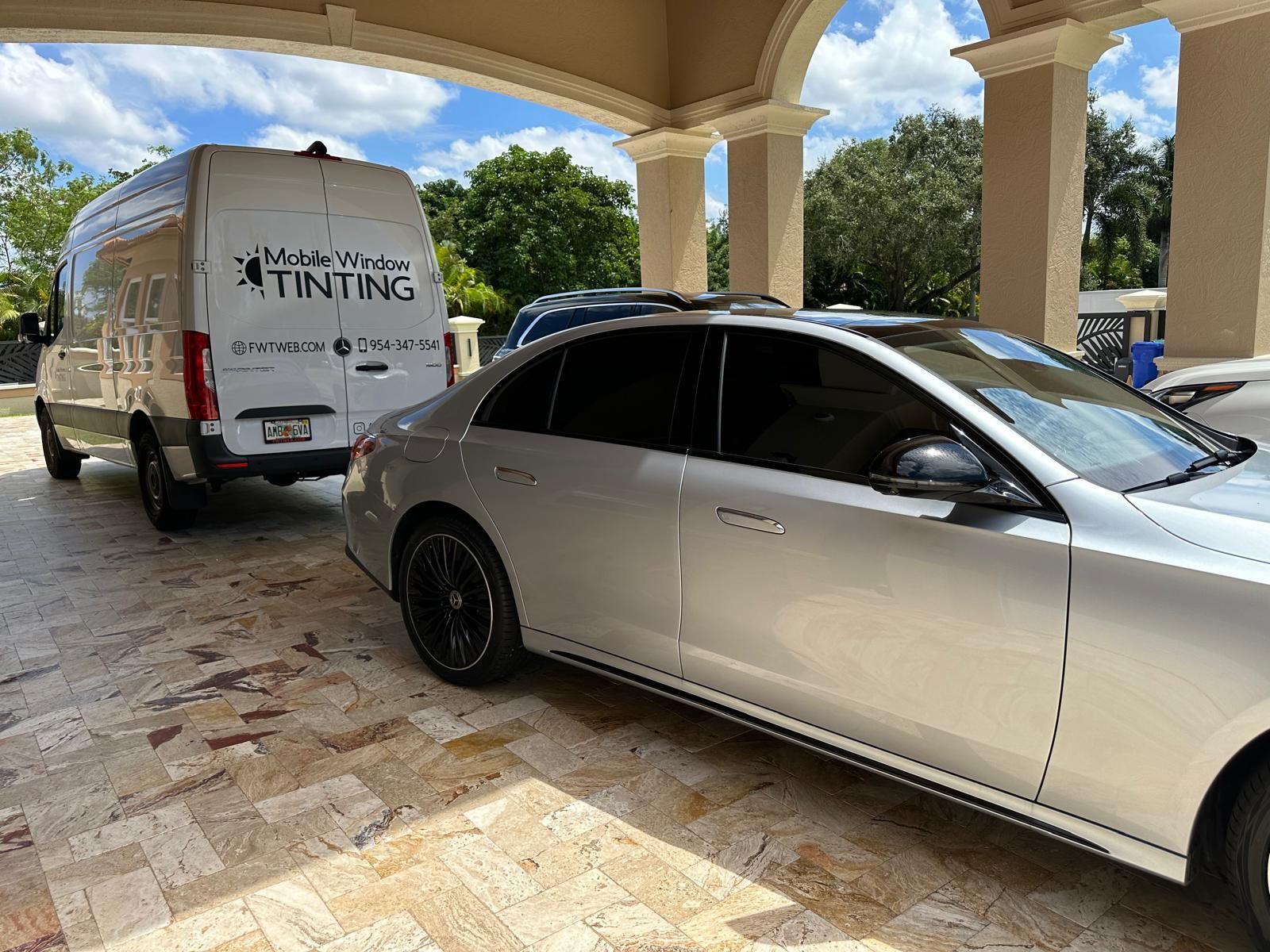 A silver car is parked next to a white van.