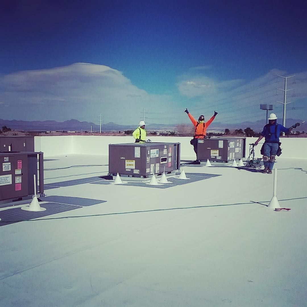 A group of people standing on top of a white commercial roof
