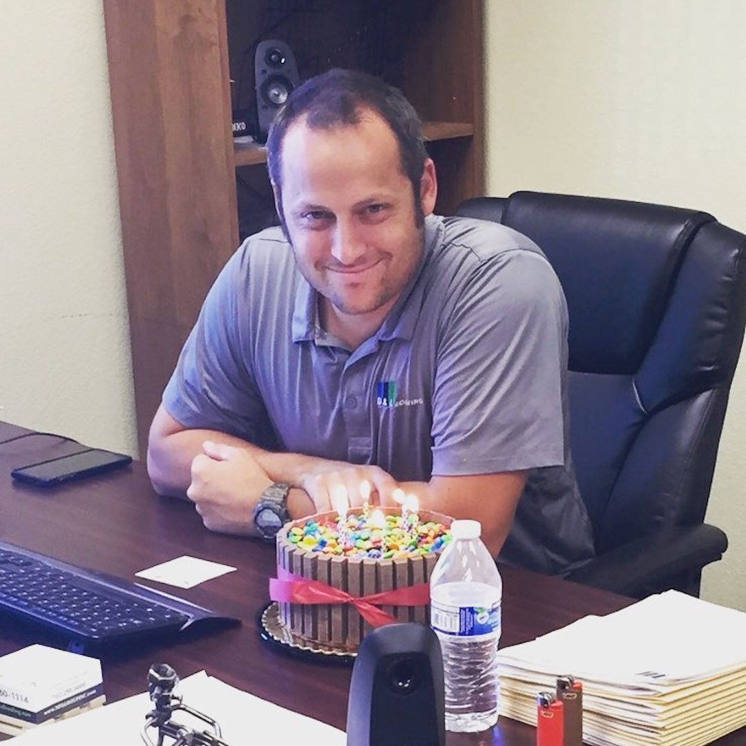 A man sits at a desk with a birthday cake on it