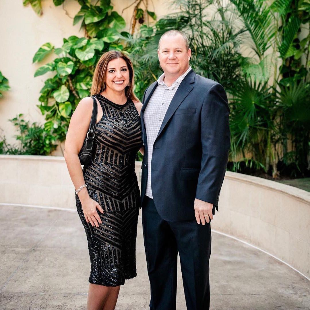 A man in a suit and a woman in a dress are posing for a picture.