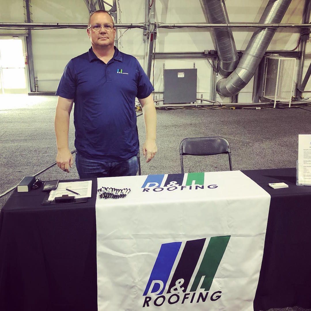 A man stands in front of a table that says d &l roofing