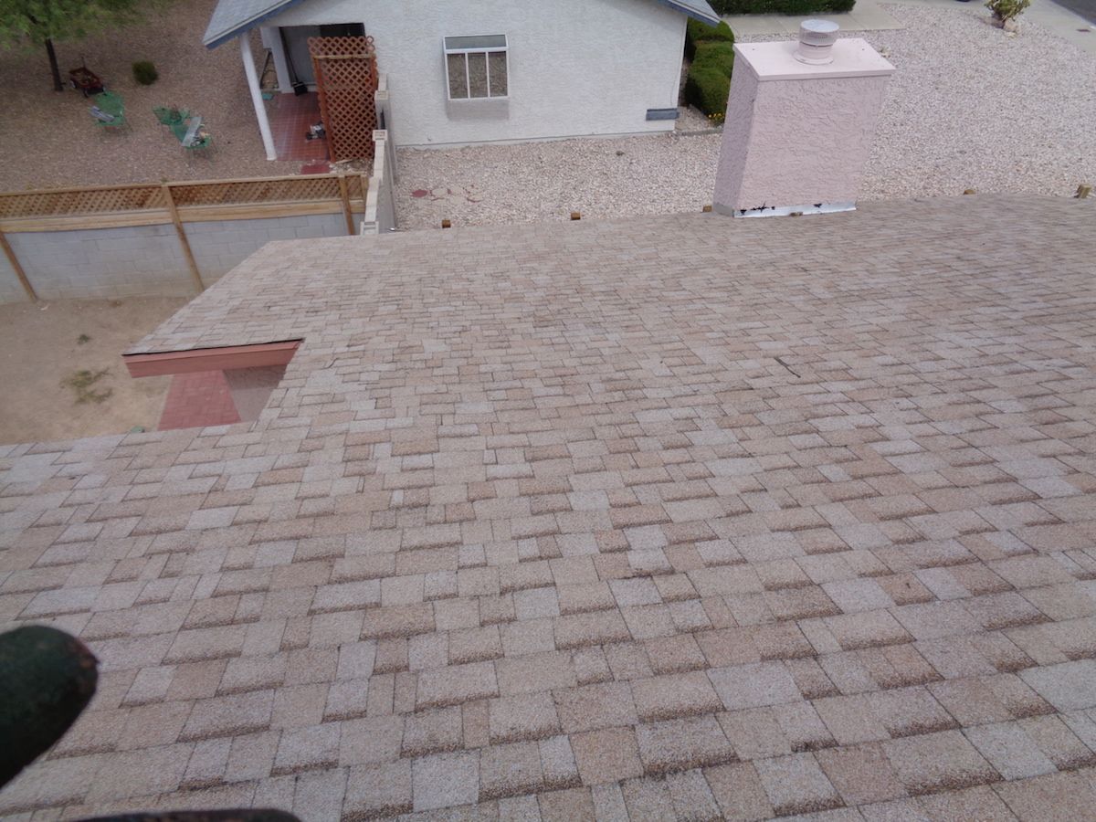 A roof with a chimney and a house in the background