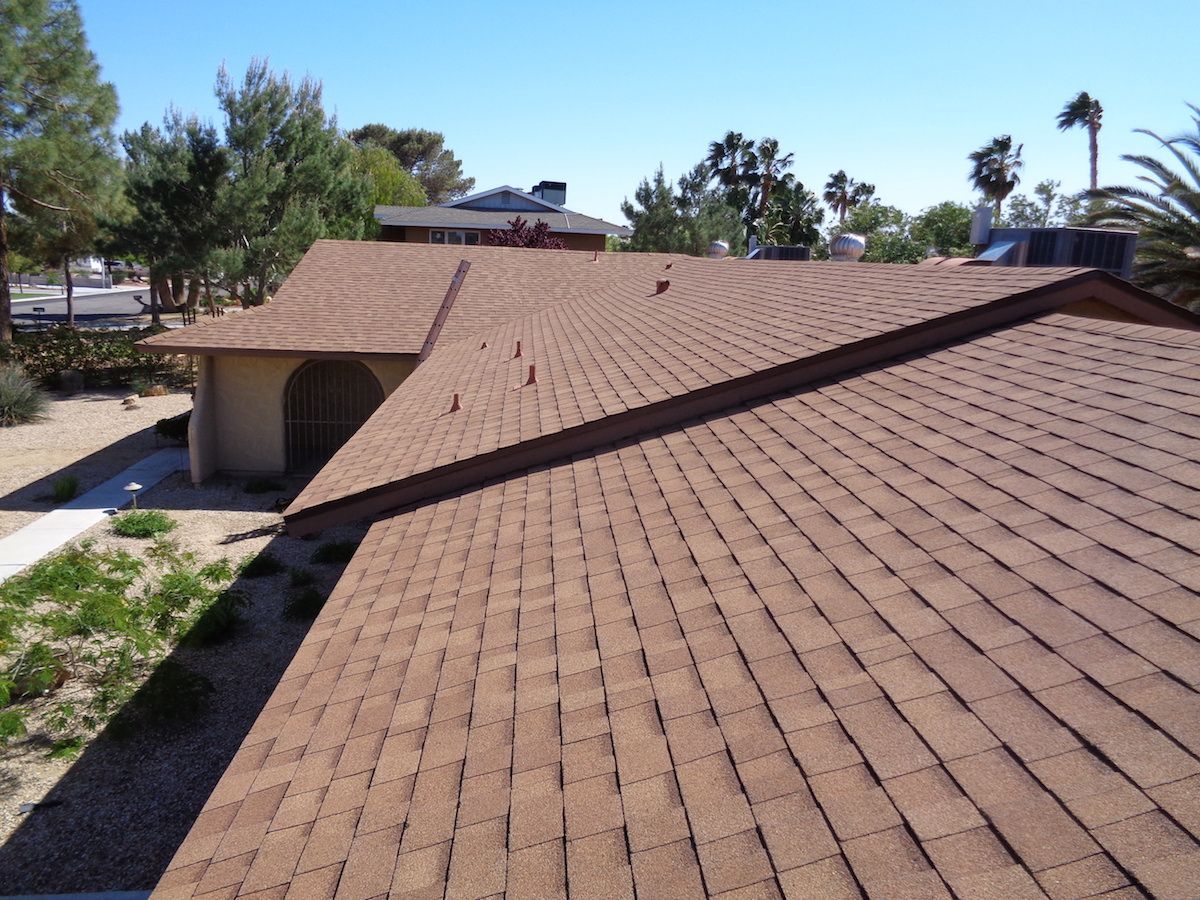 A house with a brown roof and trees in the background