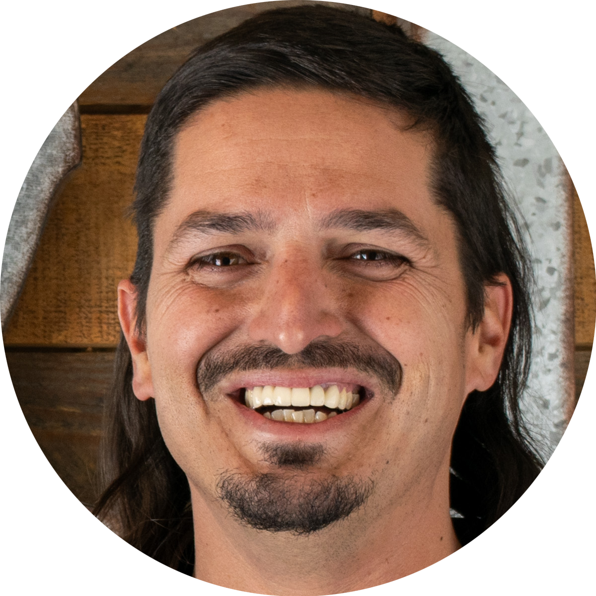 A man with long hair and a beard is smiling in a circle