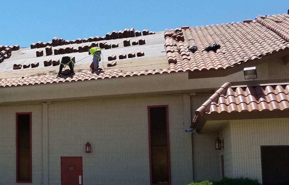 Two men are working on the roof of a house