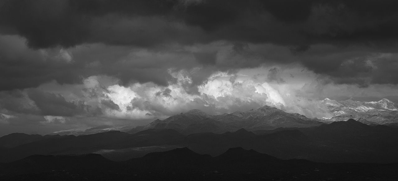 A black and white photo of a cloudy sky over a mountain range.