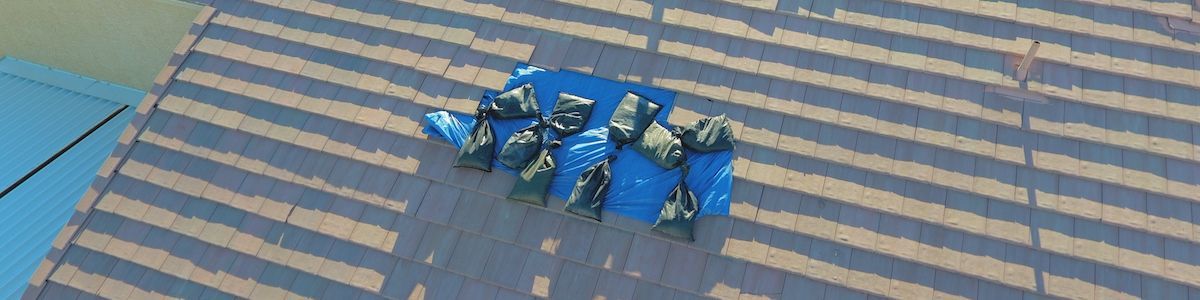 An aerial view of a group of blue tarp on a damaged roof