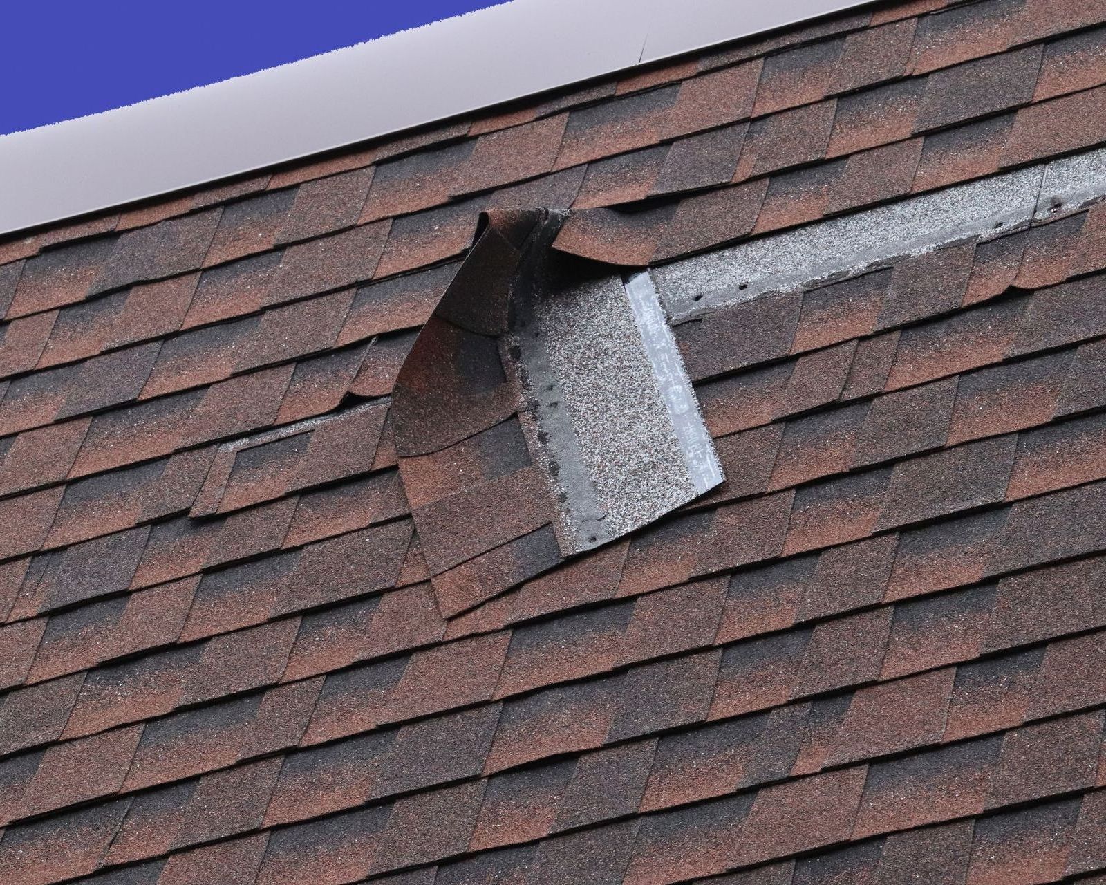 A close up of a roof with row of shingles coming off