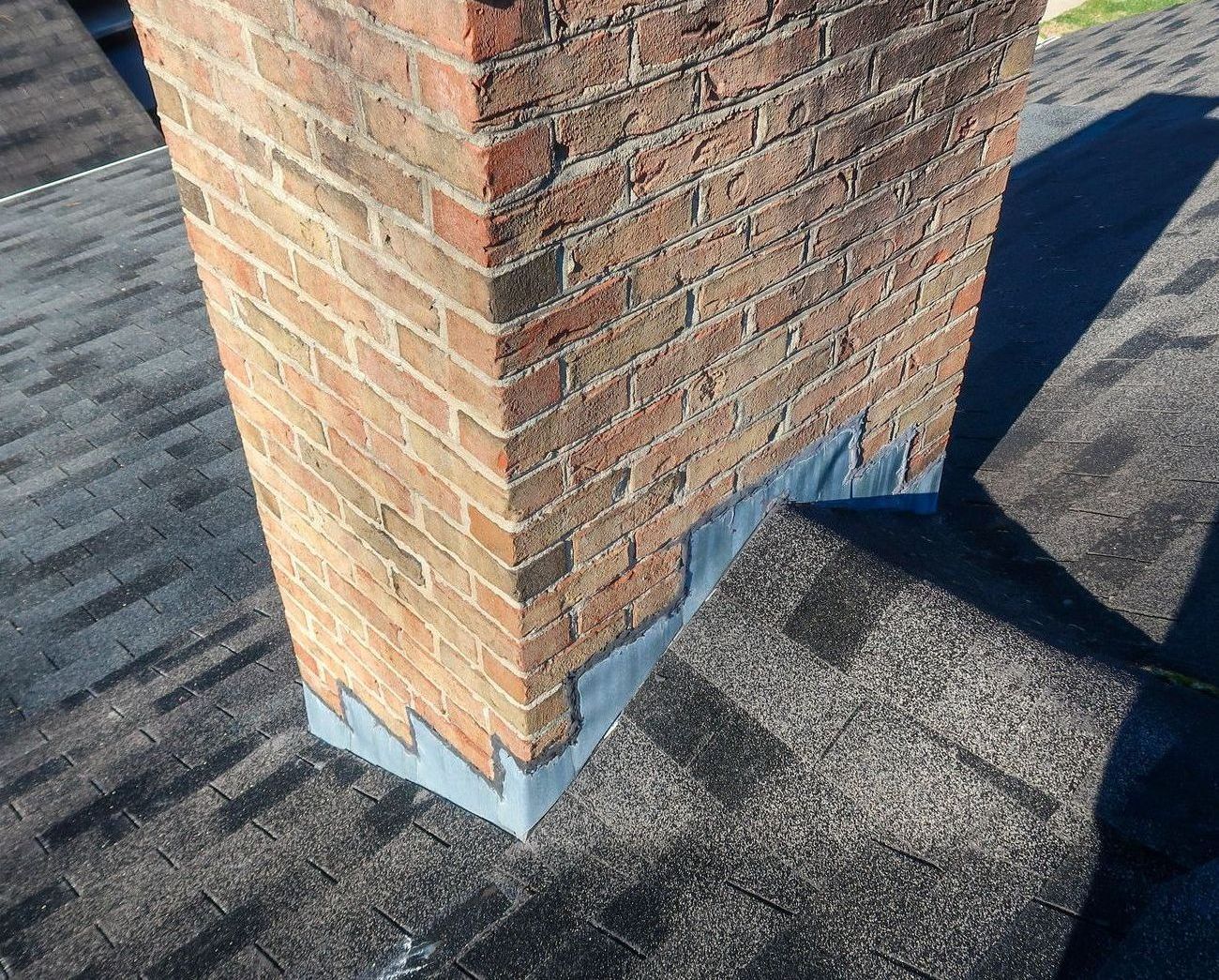 A brick chimney is sitting on top of a roof.