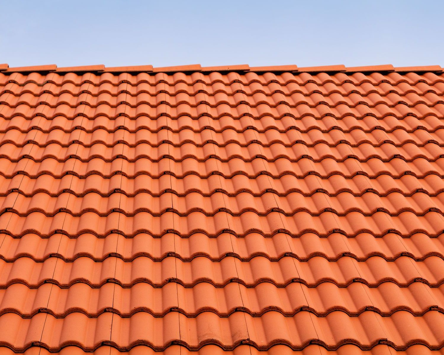 A red tiled roof with a blue sky in the background