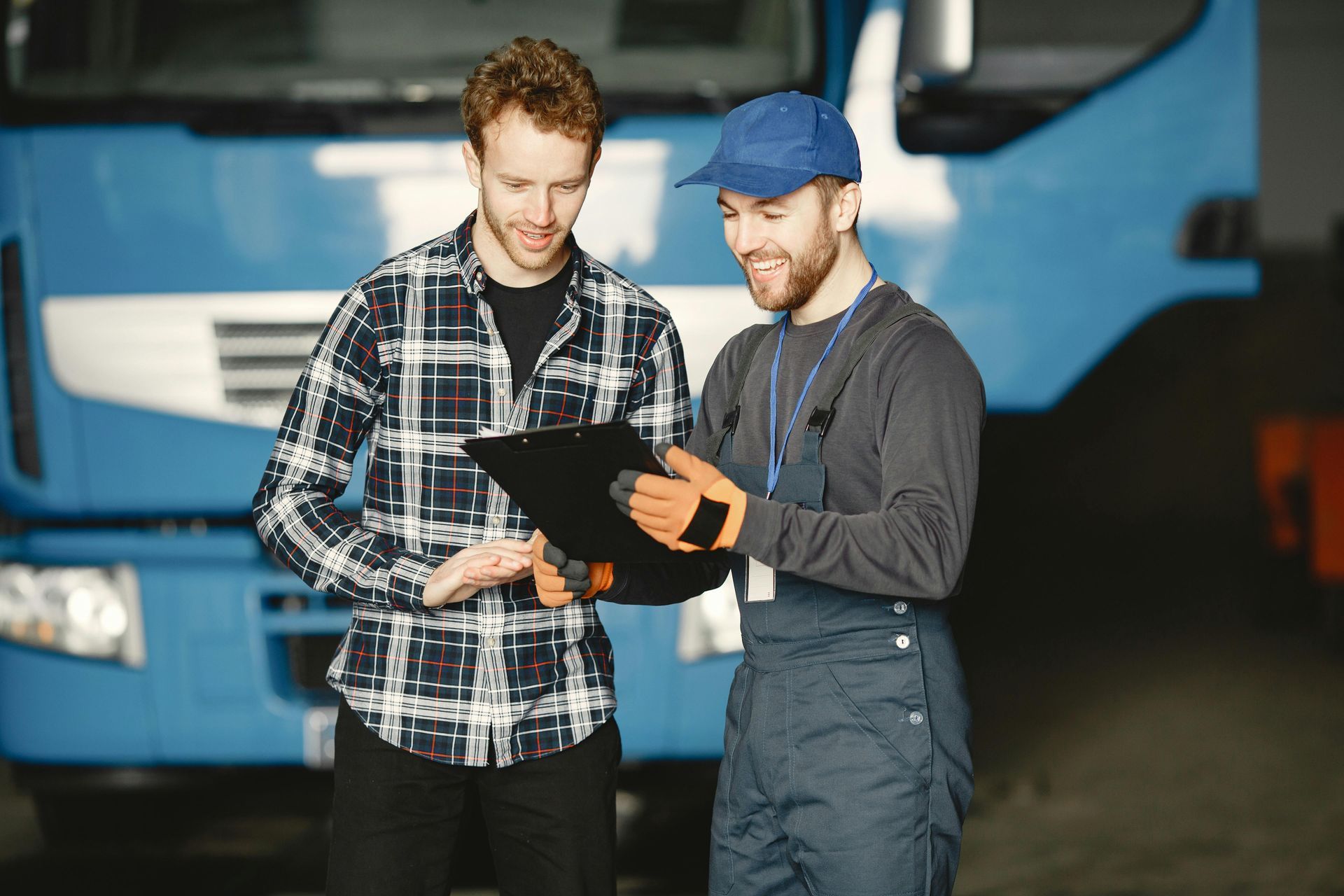 Men Are Looking at a Clipboard in Front of a Blue Truck — Noosa Mechanical in Noosaville, QLD