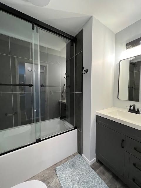 Modern bathroom with glass-enclosed bathtub shower and dark vanity with lit mirror