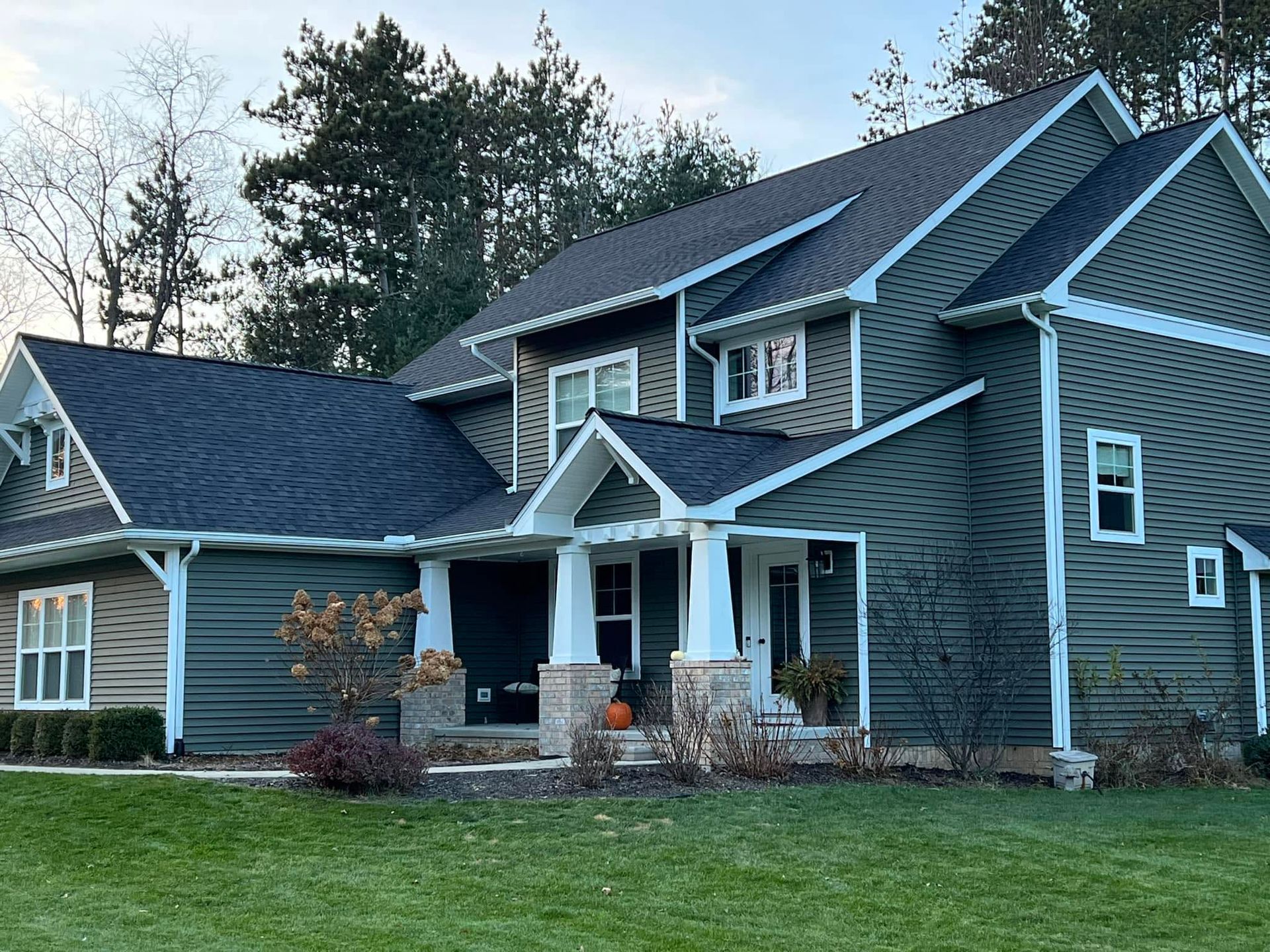 Large blue-gray suburban house with a front porch, white trim, and a well-kept lawn.