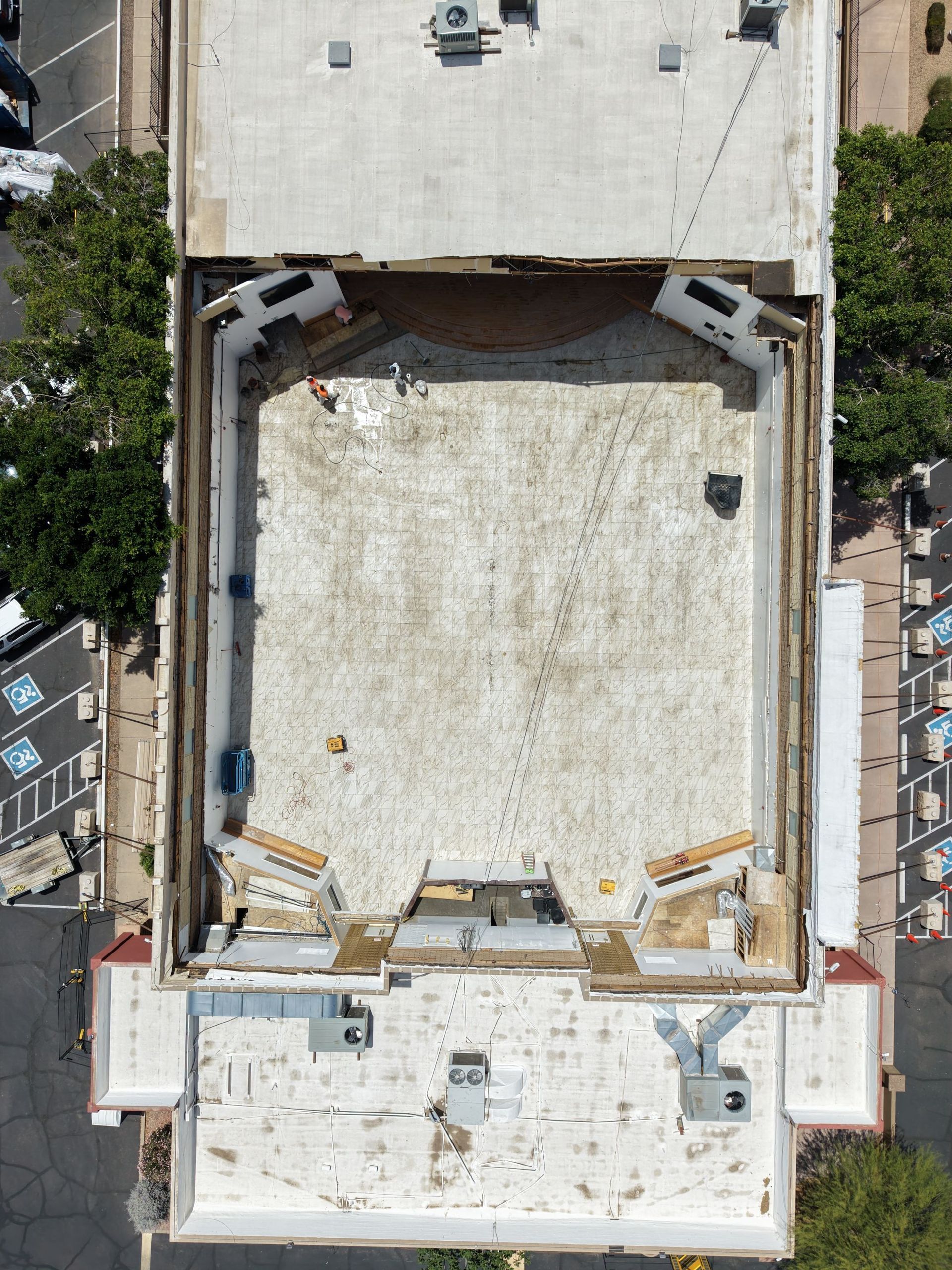 Aerial view of a flat white rooftop with HVAC units and surrounding buildings.