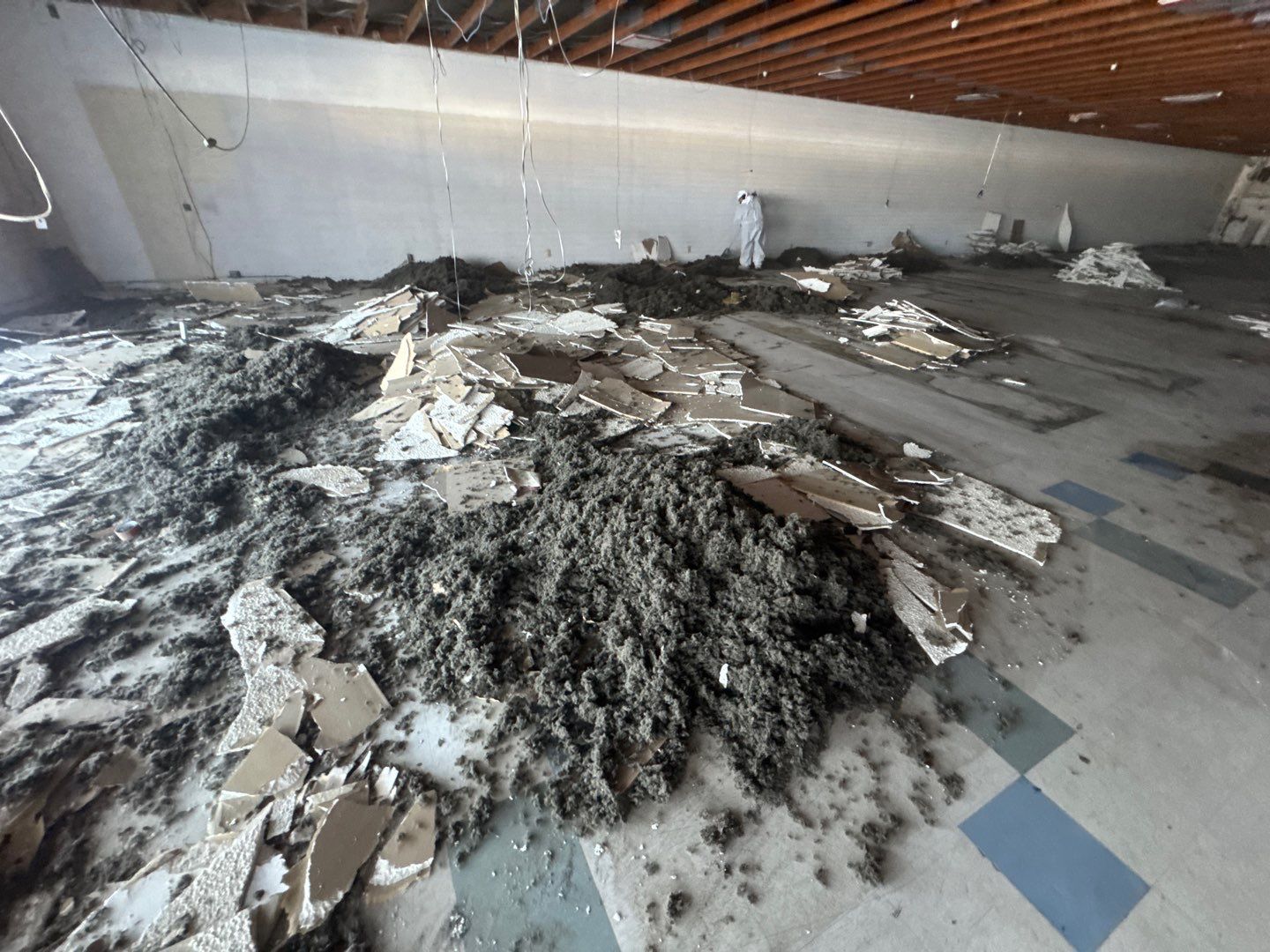 Large indoor pile of fire-damaged debris and ash on a concrete floor near a wall