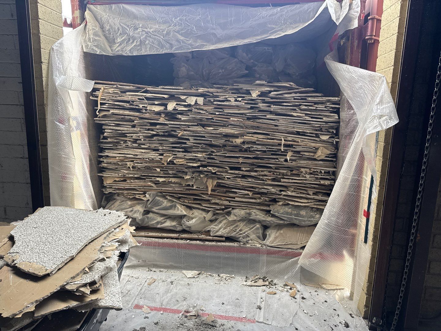 Stack of flattened cardboard boxes wrapped in plastic in a storage area