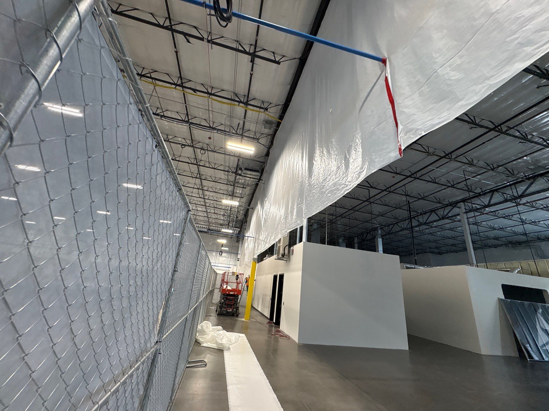 Empty warehouse corridor with chain-link fencing on the left and white partitions on the right