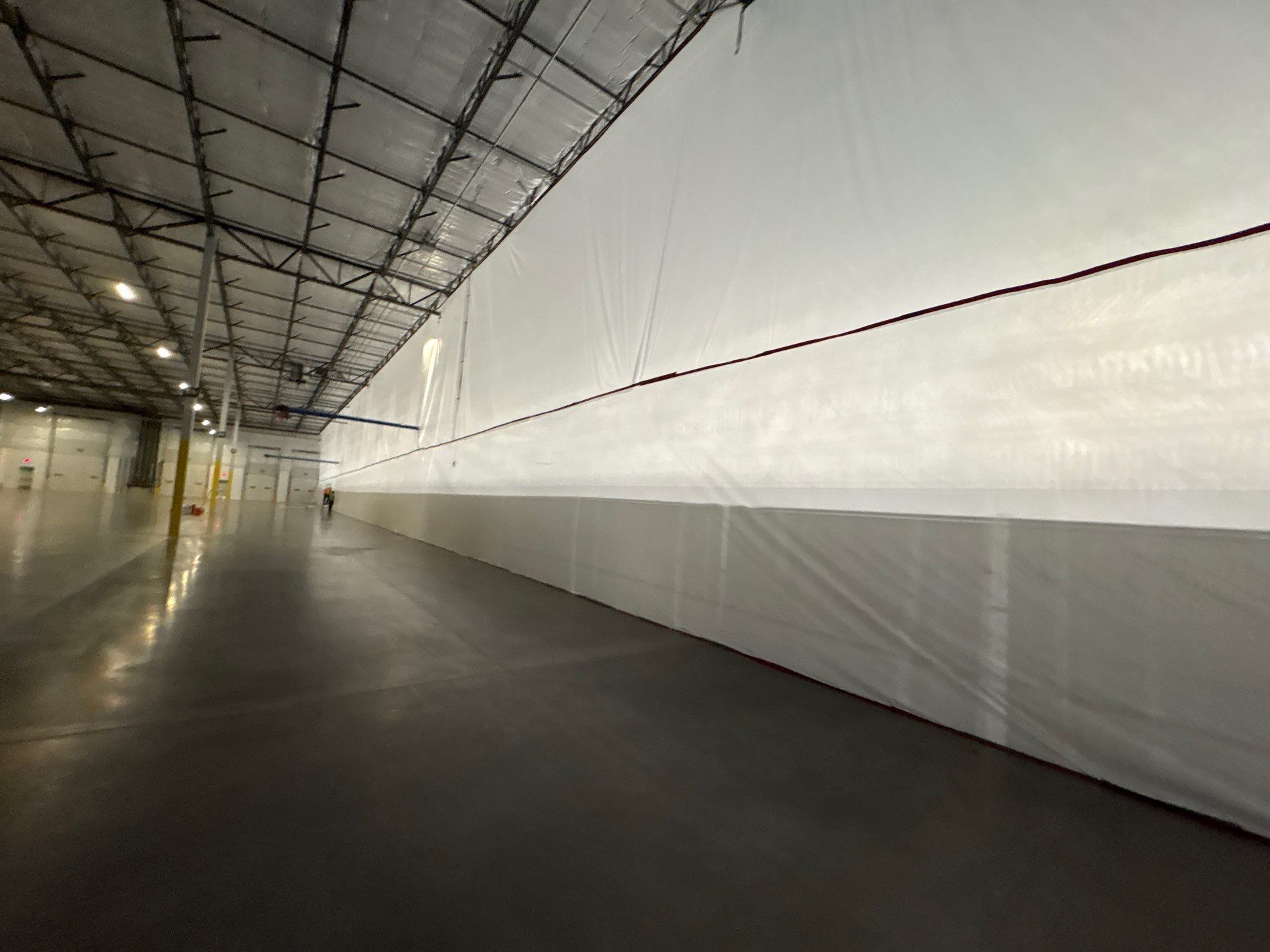 Empty industrial hallway with white walls, metal ceiling, and glossy dark floor