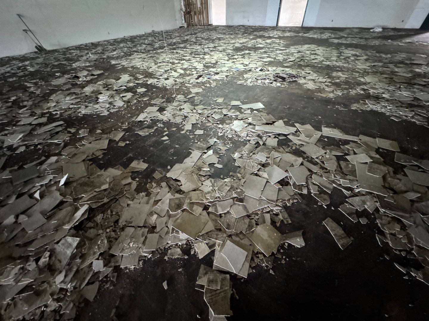 Flood-damaged room with shattered tiles and debris spread across the floor