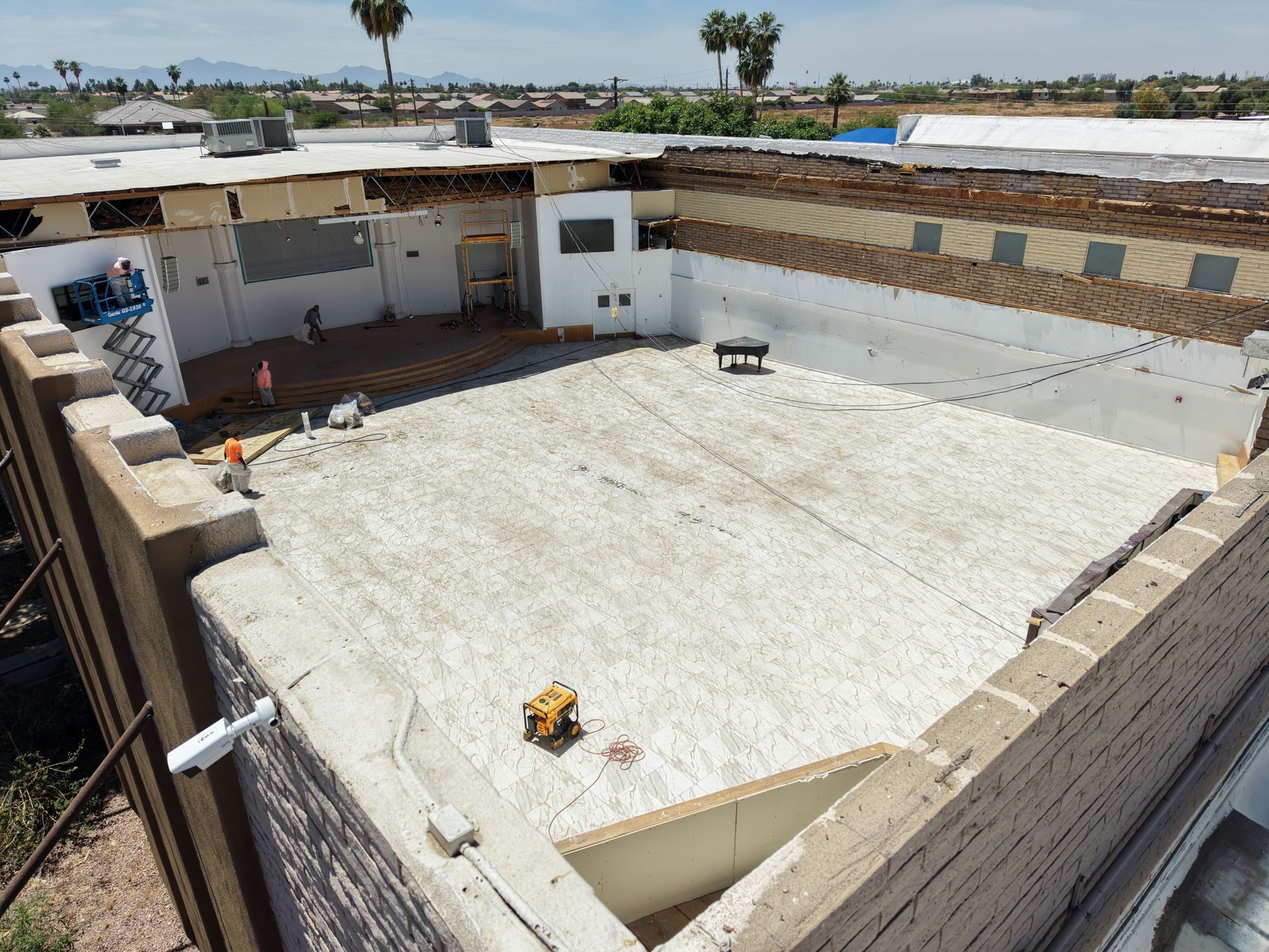 Rooftop courtyard with a large white floor, low tan walls, and a bench in the back corner.