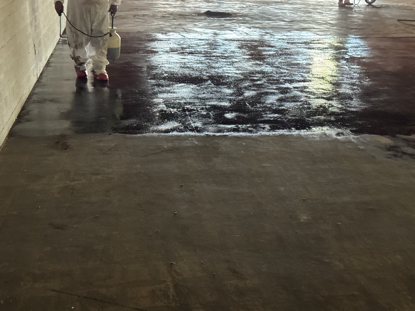 Person in white coat and pink boots walking on a wet concrete floor indoors.