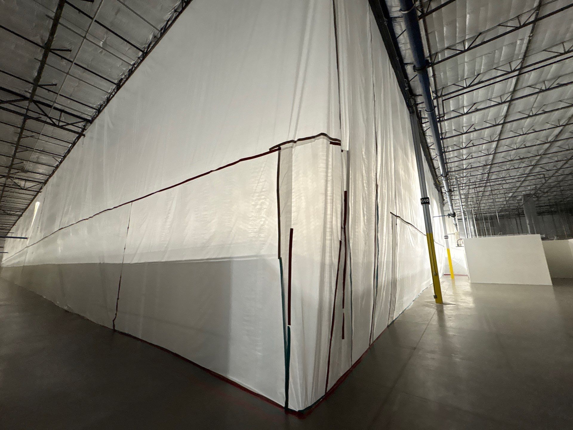 Large white fabric partitions inside a warehouse with a concrete floor and metal roof