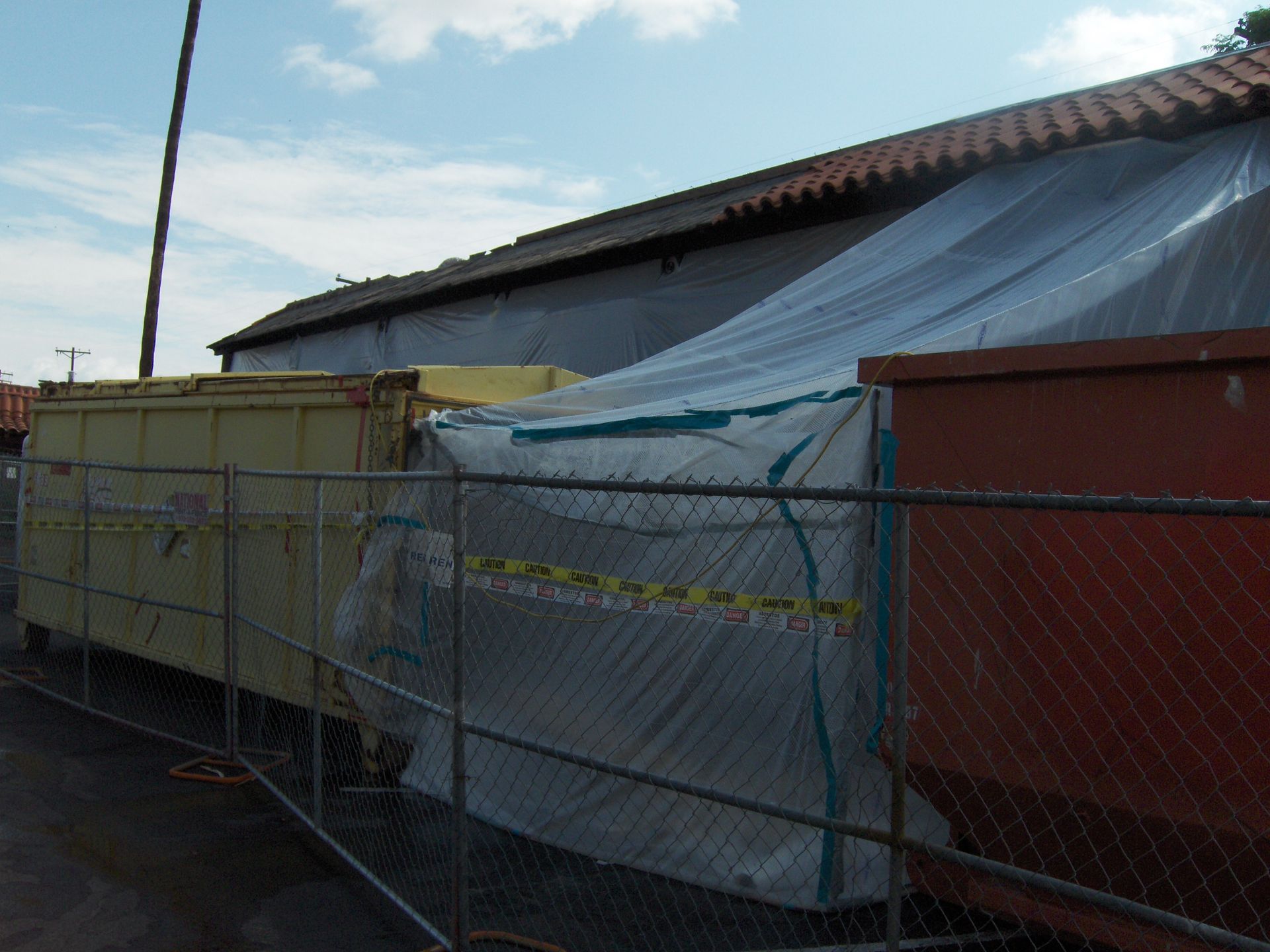 Construction site with chain-link fence and tarps covering a building exterior
