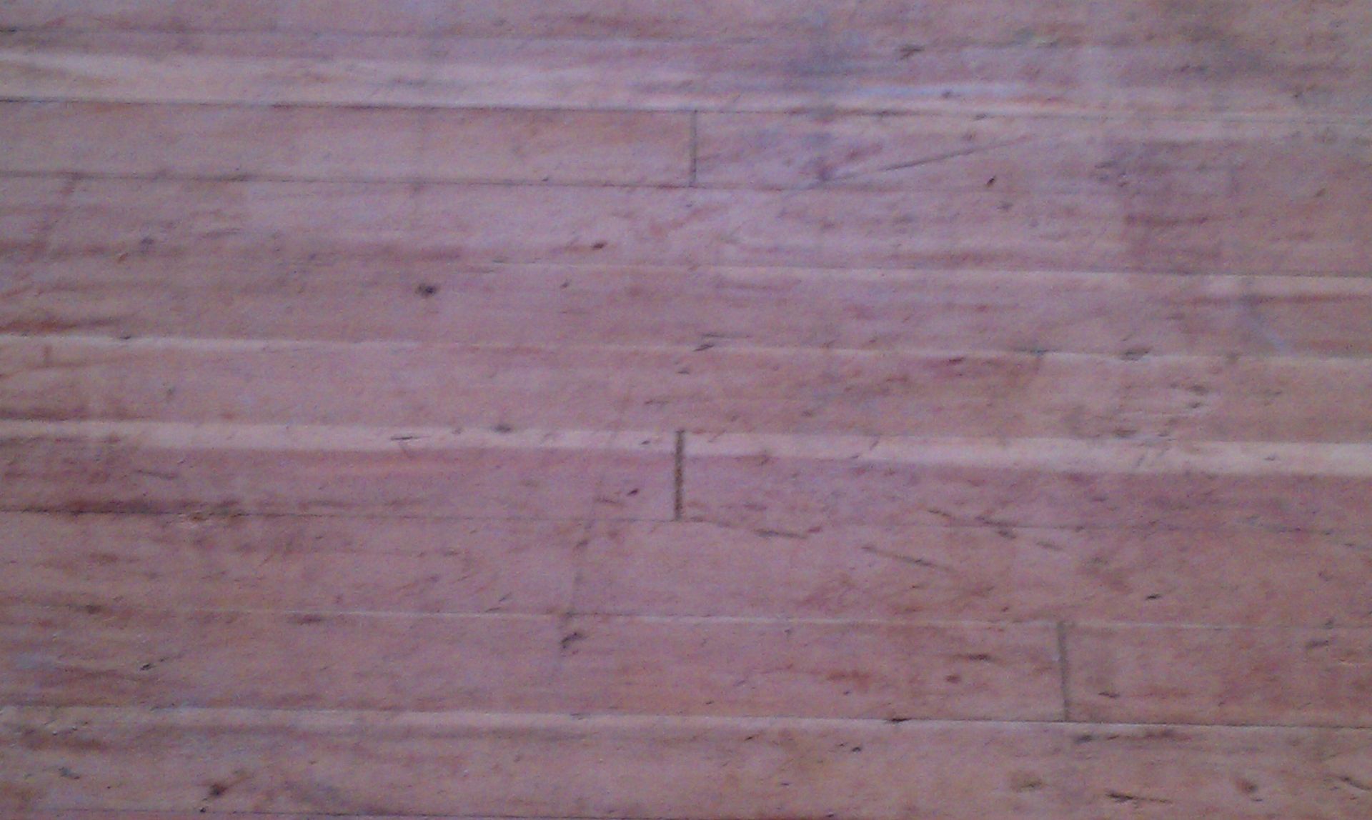 Pinkish-brown weathered wooden surface with horizontal grain and faint scratches