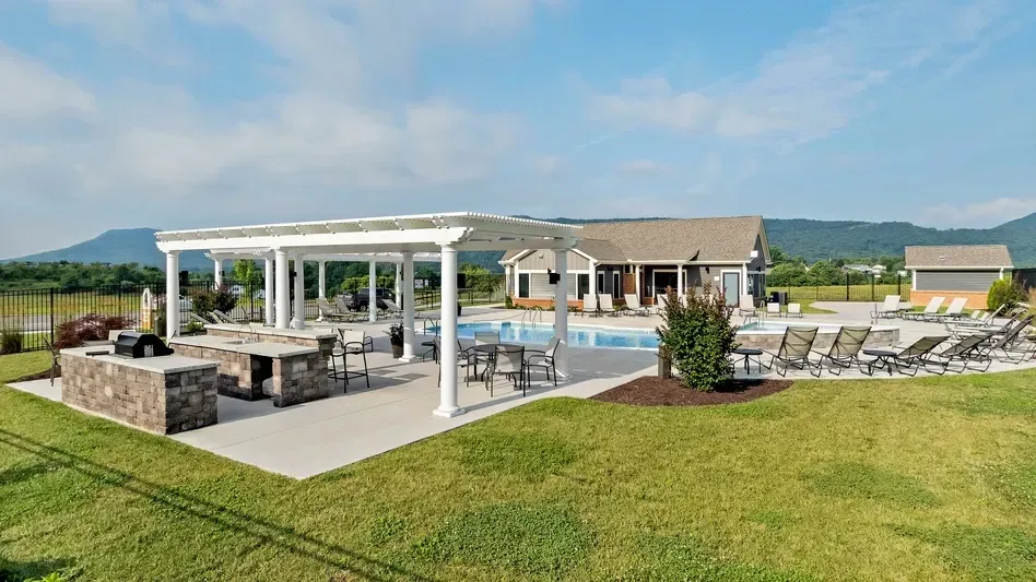 Outdoor swimming pool area with lounge chairs, tables, an outdoor kitchen with grills, and a covered patio.